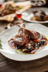 Plate with grilled ribs with sauce haute cuisine on wooden table in daylight restaurant