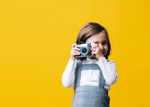 Girl Using A Photo Camera On Yellow Background