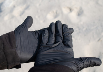 Hands in black gloves on a sand backgound