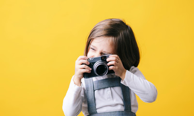 Girl using a photo camera on yellow background
