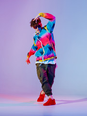 Guy dancing contemporary dance in studio. Neon light grey background. Acrobatic bboy dancer. Break dance lessons.