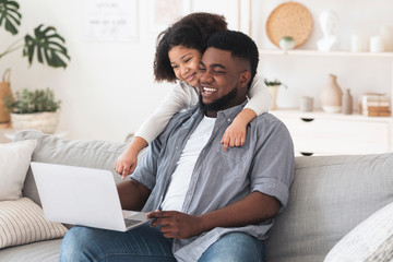 Online Shopping. Cheerful Black Father And Daughter Using Laptop At Home