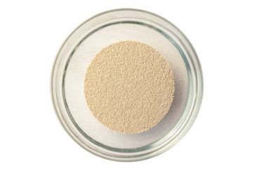 close up detail of dry dried yeast powder on a white background in a glass bowl 