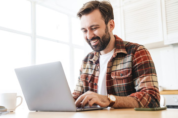 Portrait of man working with laptop and smiling while sitting at table