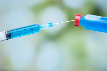 The picture of blue vaccine tube and syringe are on the blur background