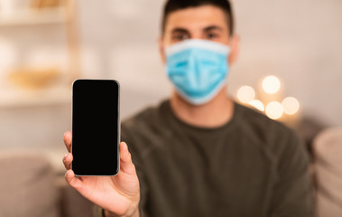 Man wearing surgical mask showing smart phone