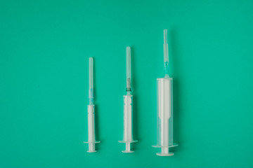 Fototapeta na wymiar three syringes different sizes on a green background