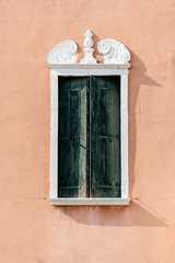Fototapeta na wymiar Window with green shutters against a wall ochre colors