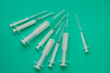 many syringes of different sizes on the green world