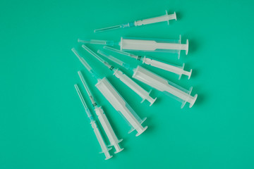 many syringes of different sizes on the green world