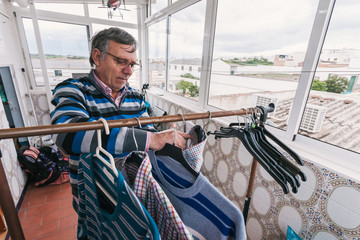 Senior man hanging clothes.