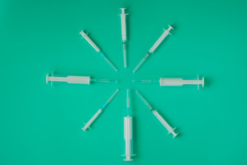 many syringes of different sizes on the green world