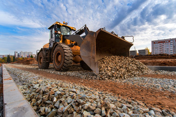 Yellow tractor at a construction site levels the road