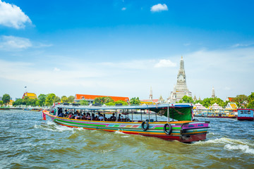 View over river Chao Phraya from boat back to temple Wat Arun, eldest temple in Bangkok. In foreground is speed longboat passing. Behind are tour boats and ferries. © banjongseal324