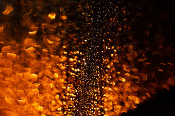 Fototapeta na wymiar Drops of rain on the glass flow down at night. Beautiful orange warm rain drops relax the mind and soothe, creates a sad atmosphere