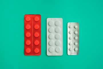 white pills in white packaging and pills in orange packaging on green background