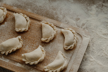 Dumplings on a wooden cutting board sprinkled with flour