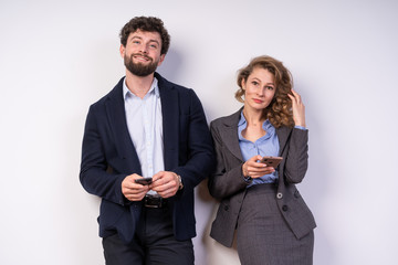 Business man and woman in costume, holding smartphone, looking at camera, smiling