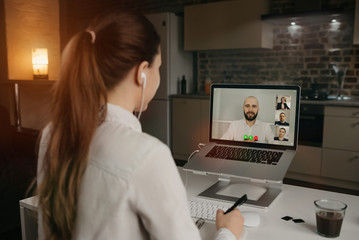 Obraz na płótnie Canvas Rearview of businesswoman in a video conference with her boss and colleagues during an online meeting. Man in a video call with partners. Multiethnic business team having a discussion in a video call 