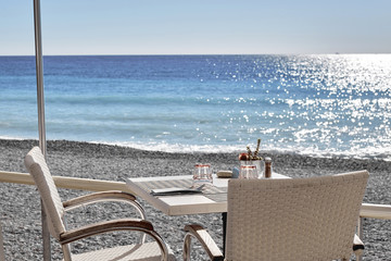 The light table is on a sandy beach by the sea. The sun reflecting in the waves of the blue sea.