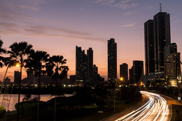 Fototapeta na wymiar skyline of panama at sunset, palms and the street in motion