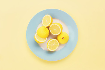 Lemons cut on top of a blue plate on a yellow background