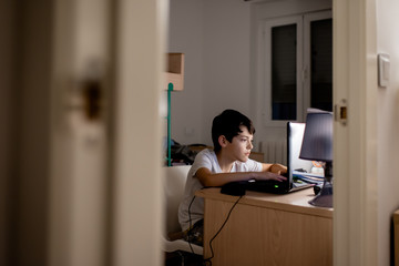 A boy using a laptop in his workspace