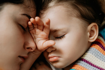 Young mother and baby of 2 years sleep together hugging, daytime sleep concept for children. Mom fell asleep with her baby while putting her to sleep