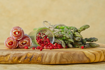 Fresh Young Asparagus with raw bacon ready for cooking. Asparagus and bacon on wood board with red pepper peas.