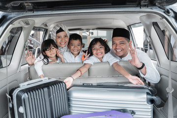 family and kids looking at the back of the trunk full with suitcase ready to go on holiday. mudik...