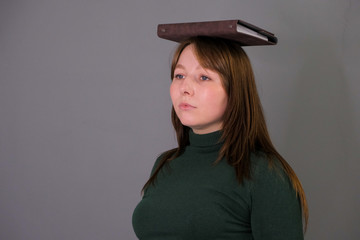 confused young beautiful woman wearing book on her head tired with studying. photography with a girl with a book