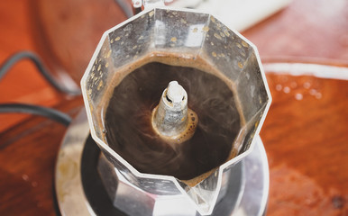 Close up of coffee boiled in the moka pot with steam.