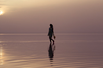 Fototapeta na wymiar Woman walking at sea at sunset. Beach Summer Holiday Vacation Traveling Relaxation Concept 