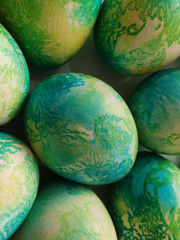 Many (mint) blue yellow eggs similar to dragon eggs, painted in colored dyes, lie on a white background.