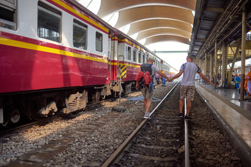 Obraz premium Bangkok, Thailand - January 2020: Rear view of a gay tourist couple on the train tracks at a railway station in Thailand