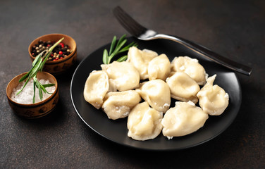 Dumplings or dumplings with cheese in a black plate on a stone background