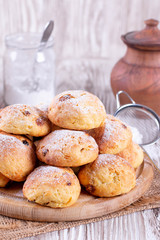 Sweet homemade cottage cheese buns with raisins and icing sugar on a white table