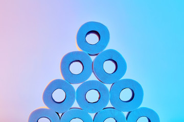 Roll of toilet papers stacked under colorful blue and pink lights