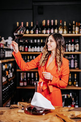 Experienced elegant sommelier woman tastes wine in restaurant. Checking taste, colour, sediments of wine
