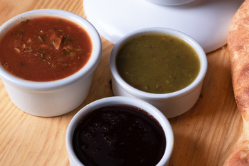 Georgian cuisine sauces in bowls close-up. Satsebeli, tkemali and narsharap on a wooden table

