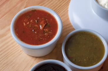 Satsebeli, tkemali and narsharap on a wooden tableGeorgian cuisine sauces in bowls close-up. 