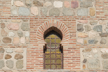 window with pointed horseshoe arch on a stone and brick facade on a building in Spain