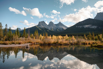Scenery of Three Sisters Mountain in autumn forest reflection on pond in Canmore at Banff national park