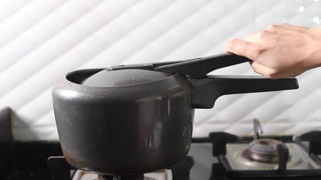 Hand Opening The Lid Of A Modern Black Pressure Cooker