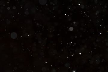 Detail of floating dust particles lit against a black background.