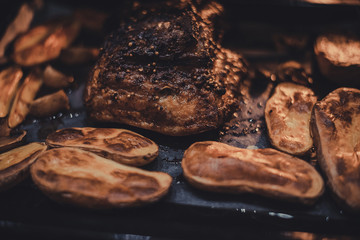 Roast pork belly with potatoes on baking tray cooked in oven. Traditional country cuisine. Baked fat meat close up. Cooked meal. Home made food. Rustic style. Gastronomy concept. Appetizing dinner