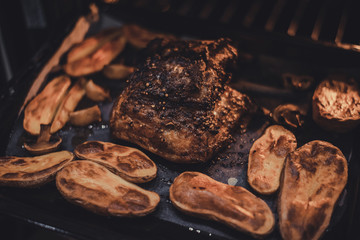 Roast pork belly with potatoes on baking tray cooked in oven. Traditional country cuisine. Baked fat meat. Cooked meal. Home made handmade food. Rustic style. Gastronomy concept. Appetizing dinner