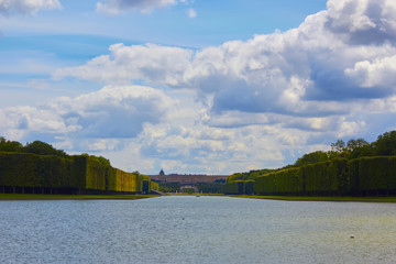 A lonely view of Versailles park, France. The geometric combination of green trees, grass areas and Grand Canal