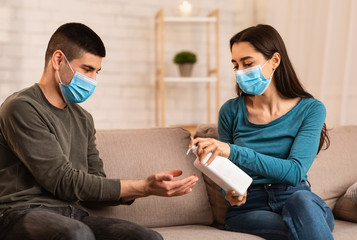 Couple sitting on couch applying anti bacteria spray