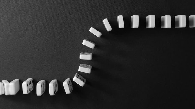 falling white dominoes against a dark background
